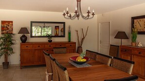 A dining room with a wooden table, chairs, a chandelier, and a large mirror.