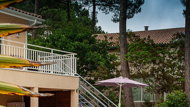A pool area with lounge chairs, a table, and a grill.