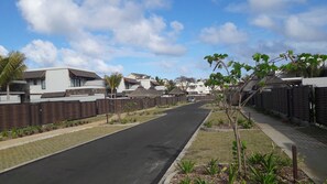 A residential street with modern houses, a paved road, and a clear sky.