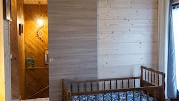 Una stanza in legno con un letto, una porta e un lampadario a parete.