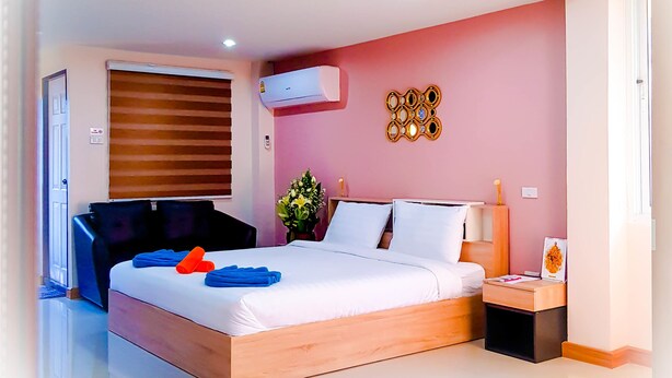 A modern bedroom with a large bed, bedside table, air conditioning unit, and a decorative wall piece. - Walking Street Residence - Boutique Suites (Pattaya)