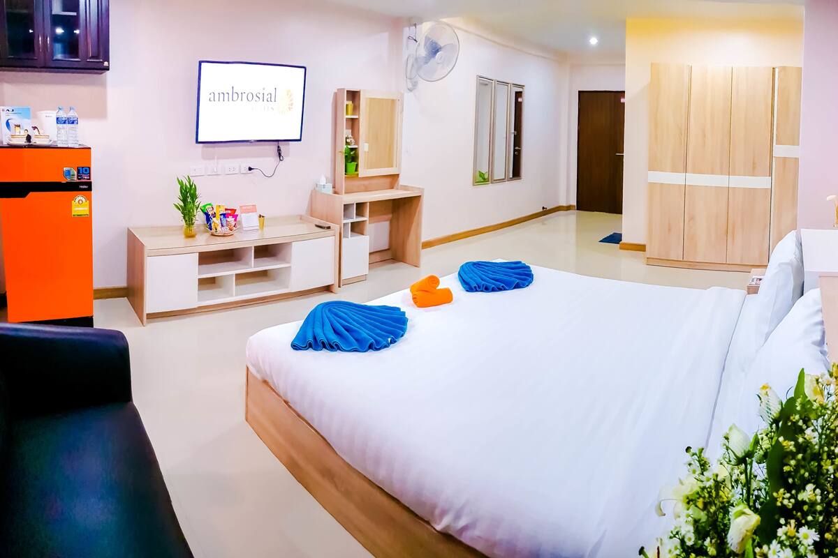 A hotel room with a bed, a desk, a wardrobe, a TV, and a minibar.