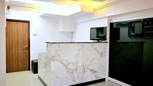 A modern kitchen with a marble countertop, a wooden door, and a black refrigerator. - Walking Street Residence - Boutique Suites (Pattaya)