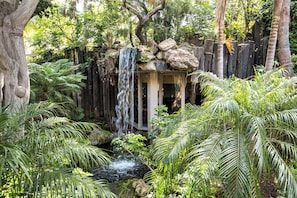 Escape to a serene garden oasis with a soothing waterfall and lush tropical plants.
