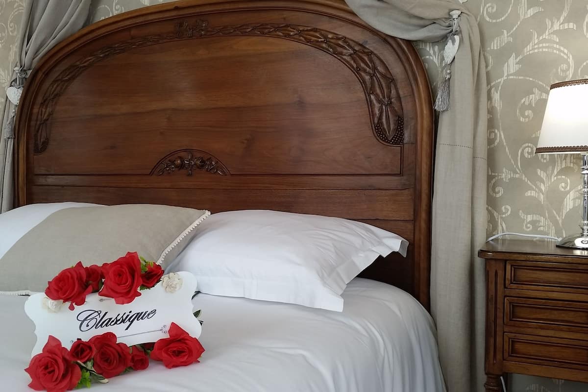 A neatly made bed with white linens, a decorative headboard, and a bedside table with a lamp.