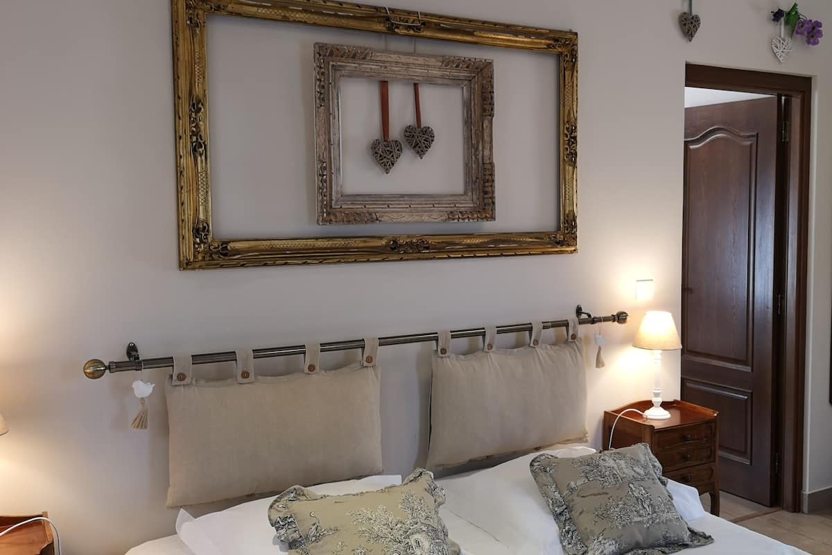 A bedroom with a bed, a nightstand, a lamp, a wardrobe, and a mirror.