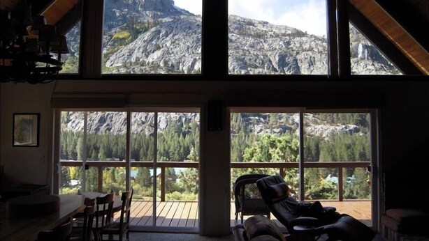 Een ruime kamer met een groot raam met uitzicht op een bergachtig landschap.