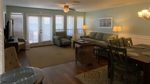 A living room with a sofa, armchairs, a dining table with chairs, a television, and a ceiling fan. - 213 Seashack- Your Dream Beach Retreat, Steps from the Shore (St Joe Beach)