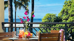A table set with a pitcher, glasses, and fruit on a balcony with a view of the ocean and palm trees. - SUMMER REDUCED! Villa 202-203 OceanView Turtle Bay (Kahuku)
