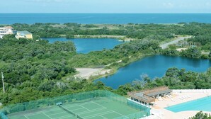 Een resort met meerdere tennisbanen, een zwembad en uitzicht op de oceaan.