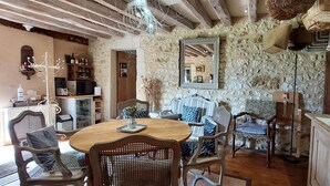 A rustic dining area with a stone wall, wooden furniture, and a large mirror. - Le Bourgis chambres d'hotes (La Chapelle-Montligeon)