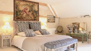 A bedroom with a large bed, a bench, a nightstand, a dresser, and a painting on the wall. - Le Bourgis chambres d'hotes (La Chapelle-Montligeon)
