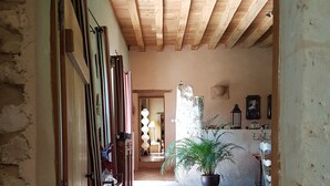A narrow hallway with wooden beams on the ceiling, a potted plant, and a brick floor. - Le Bourgis chambres d'hotes (La Chapelle-Montligeon)
