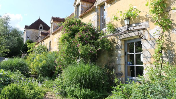 A historic building with a stone facade, a traditional pitched roof, and a small window with a wooden shutter. - Le Bourgis chambres d'hotes (La Chapelle-Montligeon)