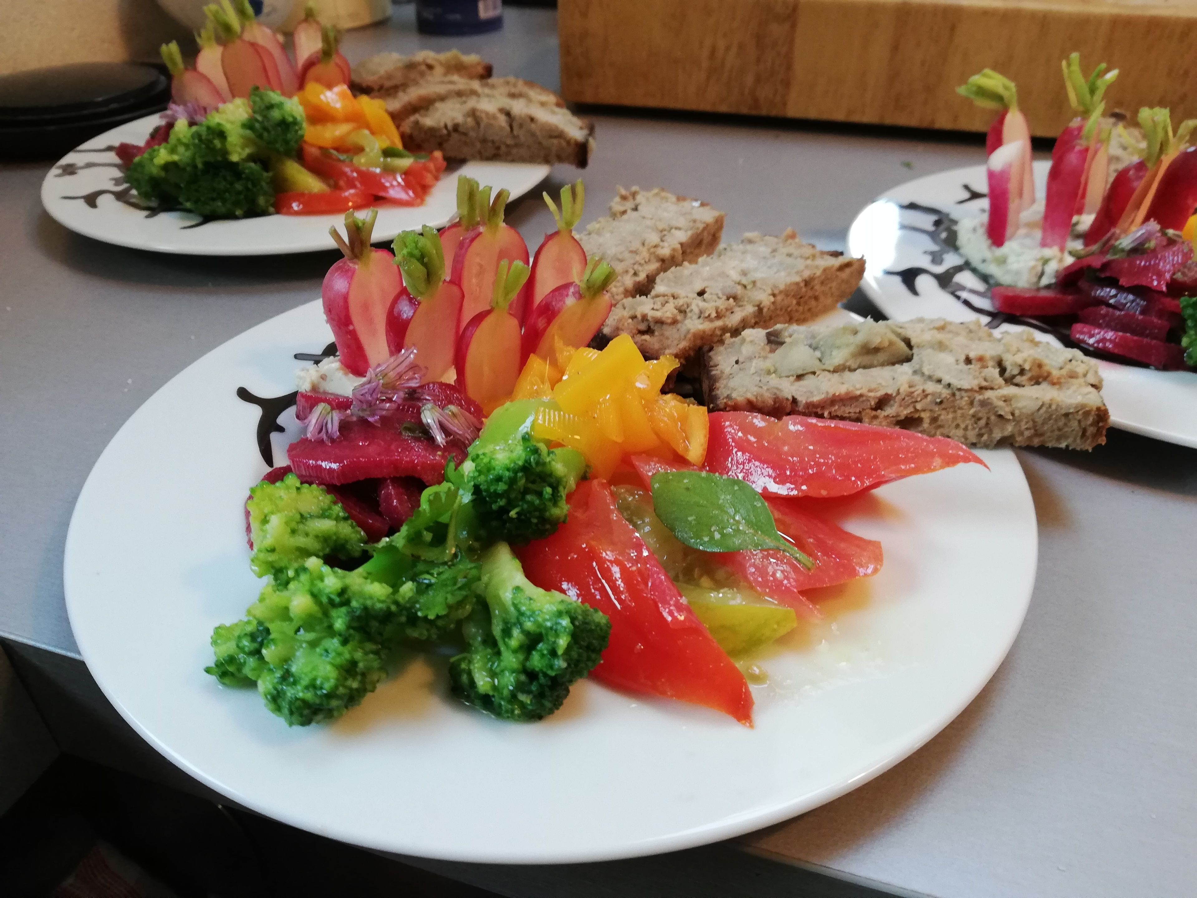 Une table dressée avec des assiettes remplies de nourriture, notamment des légumes et du pain.
