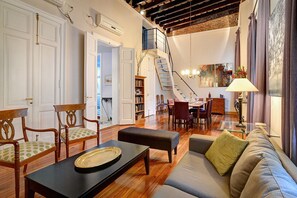 A spacious living room with a staircase leading to a loft, wooden flooring, and a dining area with a glass table. - Recoleta with History and Elegance large 2,200 sq feet. 3 Bedroom 3.5 Bathrooms (Buenos Aires)