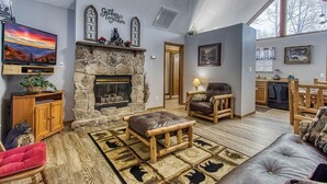 Una sala de estar acogedora con chimenea de piedra, televisor de pantalla plana y un espacio de descanso cómodo.