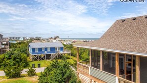 A coastal house with a large deck overlooking the ocean, a separate elevated structure, and a view of the beach and other houses. - Oceanview Home w/ Private Pool, Hot Tub, and Game Room. It's Simply Irresistible (Waves)