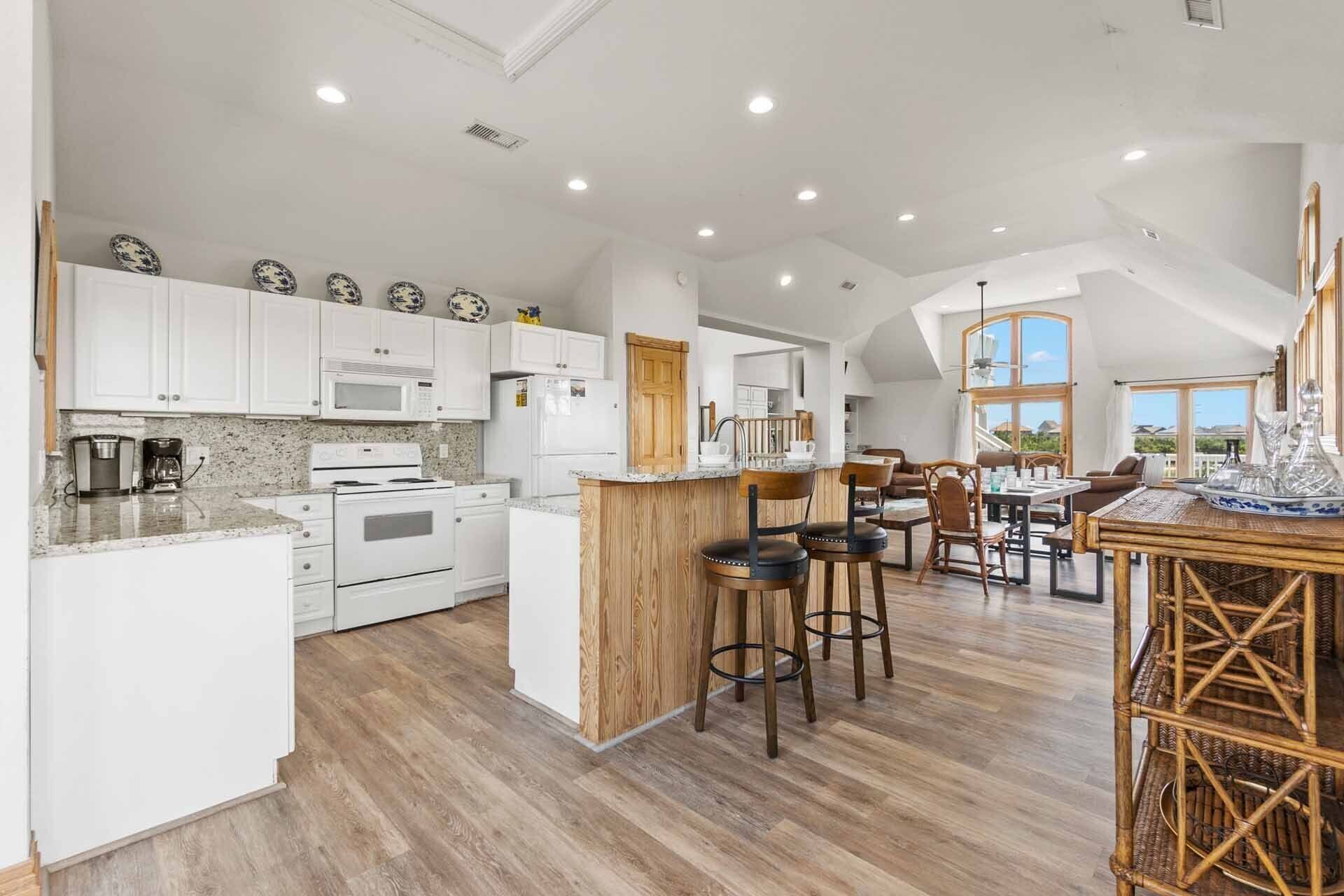 A spacious kitchen with white cabinets, a central island, and a dining area with wooden furniture.