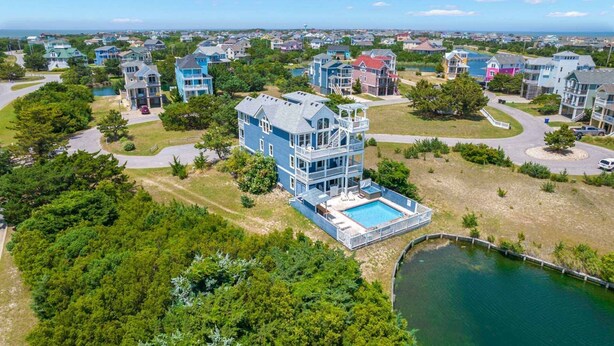 Un edificio residencial de varios pisos con un amplio balcón delantero y una piscina.