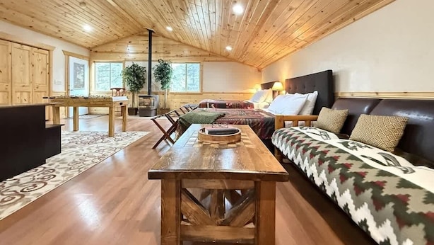 A spacious room with a wooden ceiling, a large bed, a sofa, and a dining table.