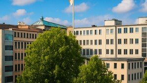 A multi-story building with a flagpole, large windows, and a green roof. - Arena Suites Hannover (Hannover)