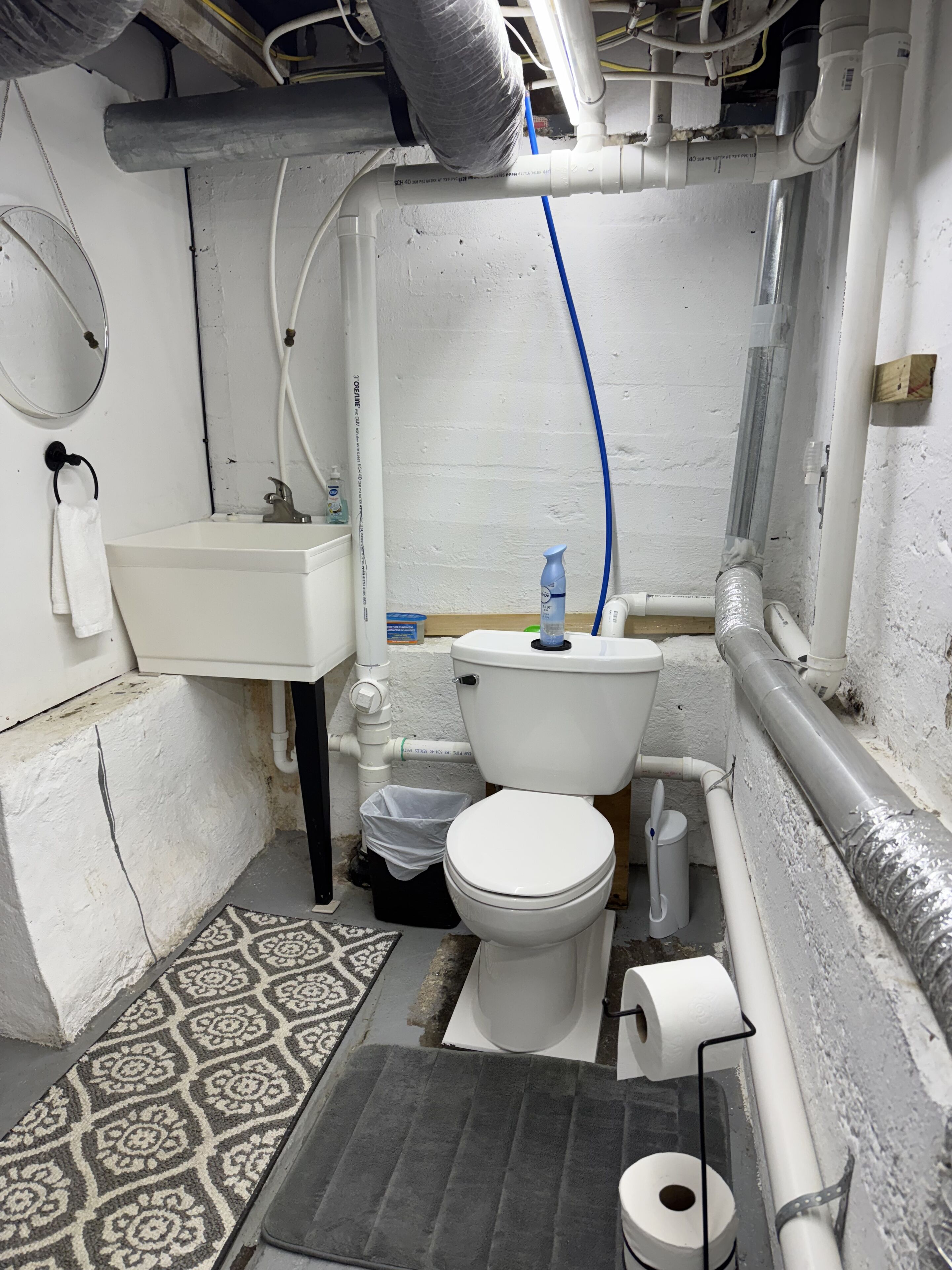 A small, compact bathroom with a toilet, sink, and shower area.