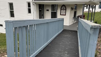 A house with a covered porch and a wooden deck leading to the entrance.