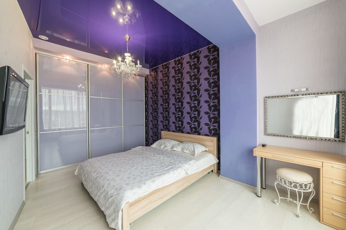 A bedroom with a bed, a vanity with a mirror, and a chandelier.