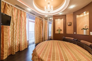 A spacious bedroom with a large bed, a television, and a chandelier. - Most City Apartments (Dnipro)