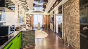 A modern living room with a spiral staircase, a dining area, and a kitchen with a green countertop. - Most City Apartments (Dnipro)