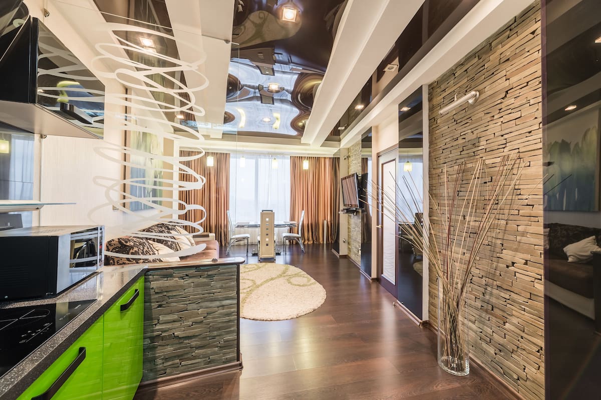 A modern living room with a spiral staircase, a dining area, and a kitchen with a green countertop.
