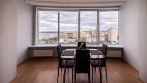 A dining area with a large window, a table, and four chairs. - Most City Apartments (Dnipro)