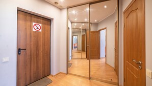 A hallway with a wooden door, a sliding mirror door, and a no-smoking sign. - Most City Apartments (Dnipro)