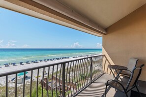 A balcony with a view of the beach and ocean.