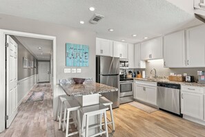 A modern kitchen with white cabinets, stainless steel appliances, and a granite countertop. - 39- Recharge your happiness in this beautiful BEACH FRONT Condo! (Destin)