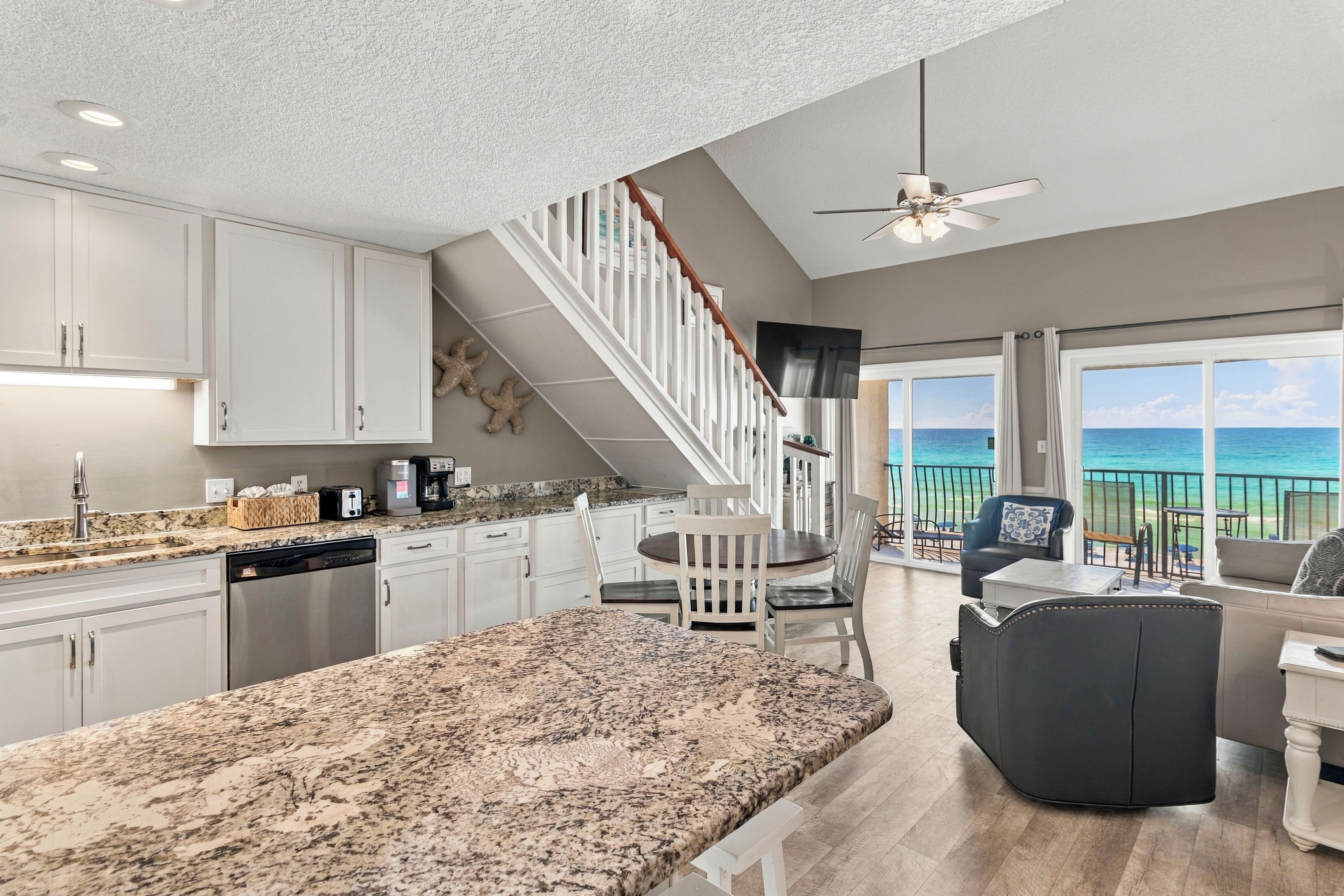 A modern kitchen with granite countertops, white cabinetry, and a built-in dishwasher.