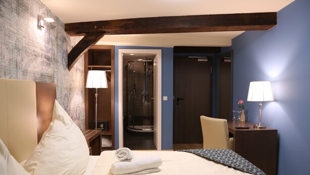 Een hotelkamer met een bed, een bureau, een stoel, een douche en een deur.