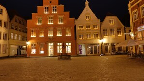 Een geplaveid plein met historische gebouwen, een fontein en terrasjes.