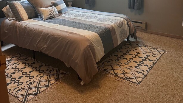 A bedroom with a large bed, two windows with curtains, a wall clock, and a ceiling fan. - Peaceful Mountain Cabin Near Lake Pactola – Perfect for Families or Couples (Rapid City)
