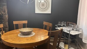 A dining area with a round wooden table, six chairs, a chandelier, a wall-mounted artwork, and a wine rack. - Peaceful Mountain Cabin Near Lake Pactola – Perfect for Families or Couples (Rapid City)