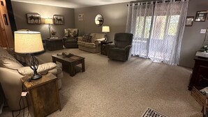 A living room with a high ceiling, a fireplace, a sofa, a coffee table, and a patterned rug. - Peaceful Mountain Cabin Near Lake Pactola – Perfect for Families or Couples (Rapid City)