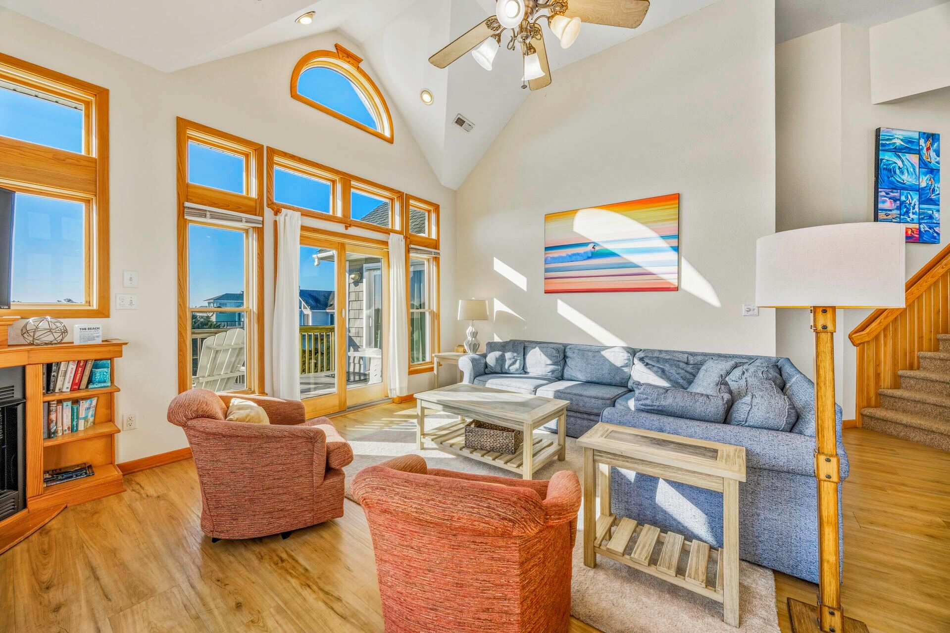 A spacious living room with a large window, a fireplace, a sofa, and a staircase.