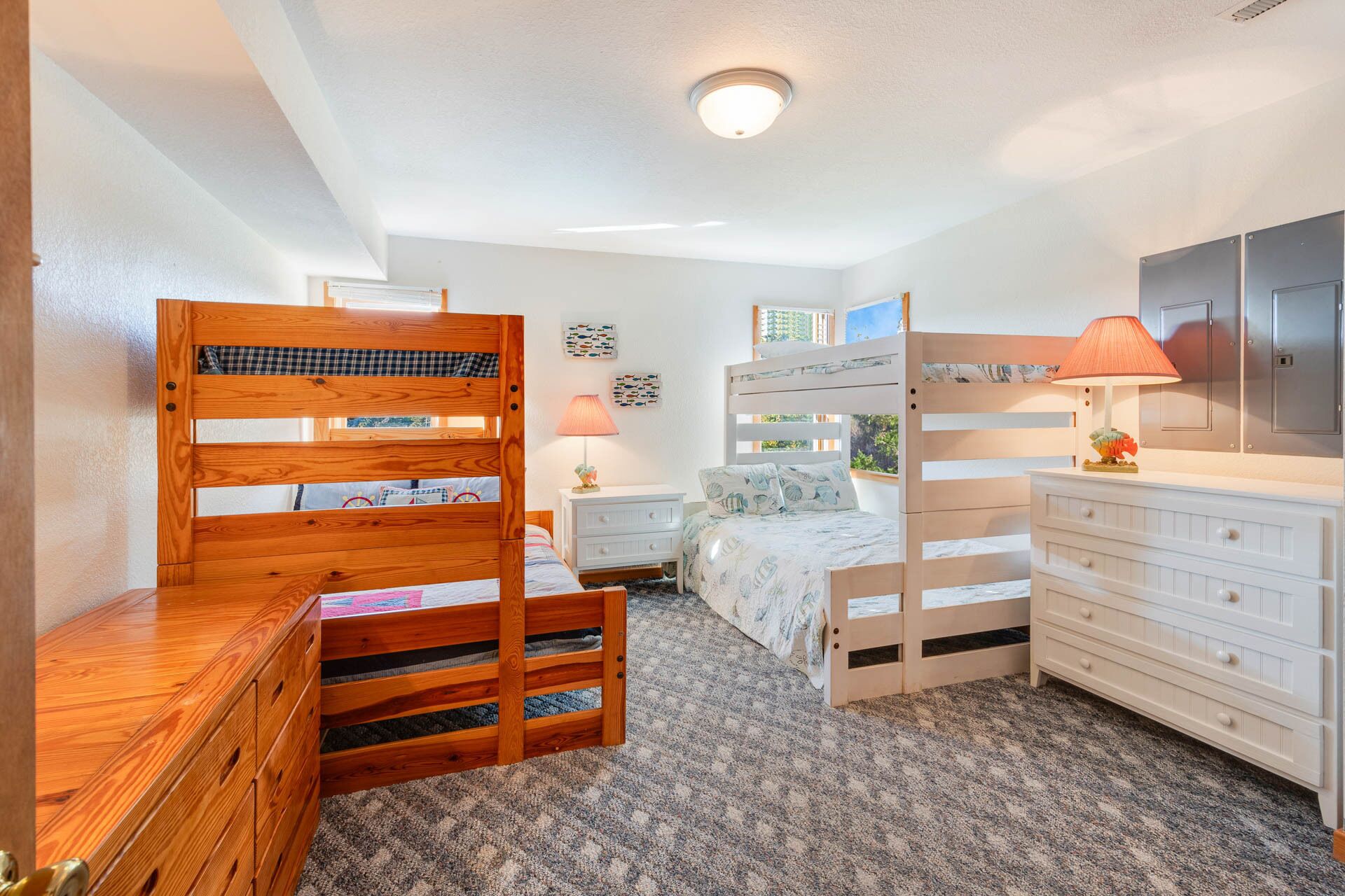 Une chambre avec des lits superposés, une chaise en bois, une commode et une table de chevet.