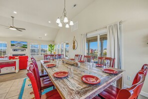 A dining area with a long wooden table set for six, red chairs, and a chandelier.