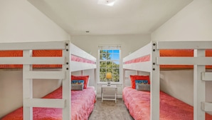 Een kamer met stapelbedden, een raam met uitzicht en een tafeltje met een lamp.