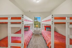 Een kamer met stapelbedden, een raam met uitzicht en een tafeltje met een lamp.