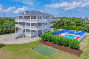 A multi-story building with a pool and a green lawn area.