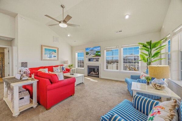 A spacious living room with a red sofa, blue-striped sofa, and a fireplace.