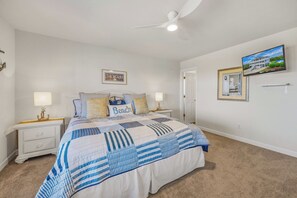 A bedroom with a bed, nightstands, a ceiling fan, a framed picture, and a window.